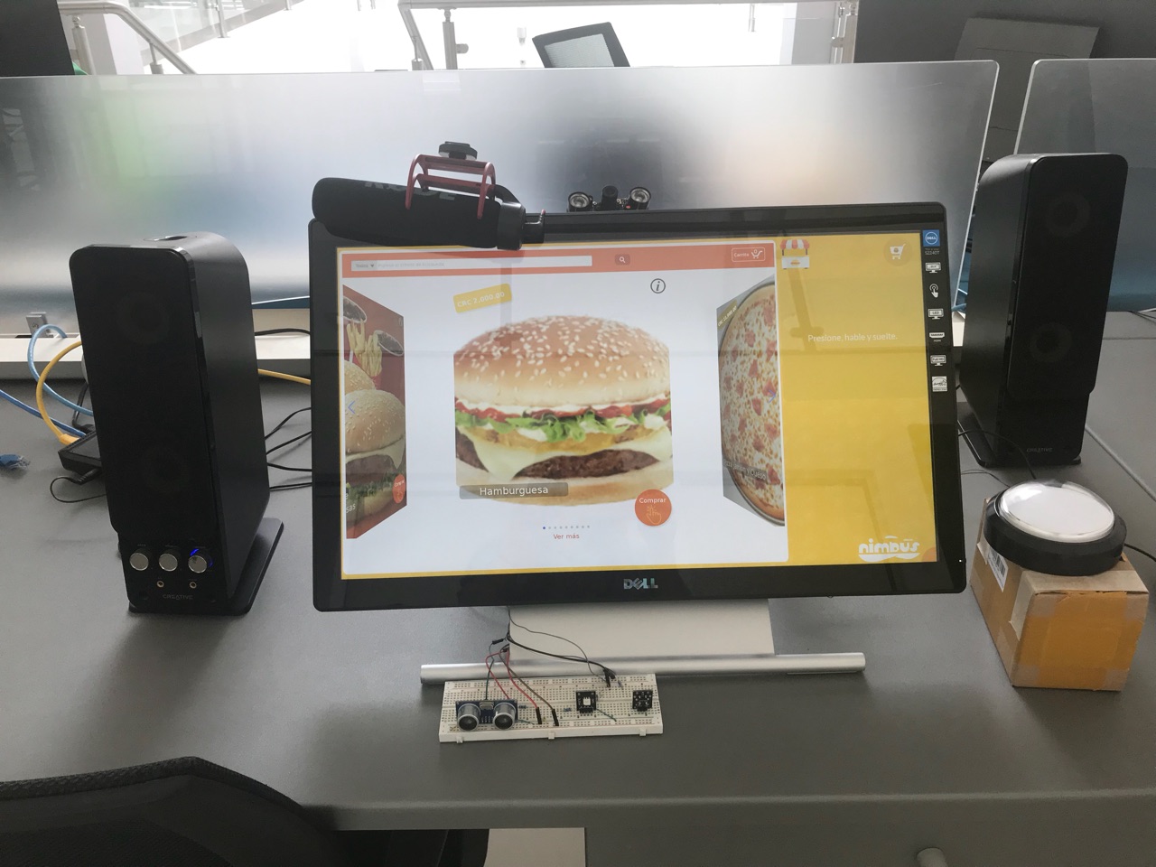 The finished kiosk prototype showing a burger on its touch screen, with sensors on the breadboard in front